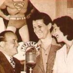 Joan, Beck and Collyer posing for a photo. Joan is wearing a black dress and holding a bouquet of flowers. Bud Collyer in a suit and tie.