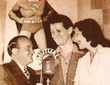 Joan, Beck and Collyer posing for a photo. Joan is wearing a black dress and holding a bouquet of flowers. Bud Collyer in a suit and tie.