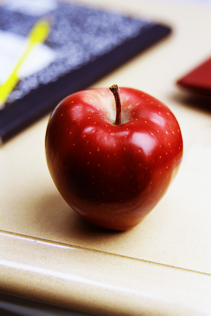 "An apple sitting on a school teacher's desk"