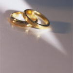 Two gold wedding bands resting on a wooden table, symbolizing commitment, love, and marriage.