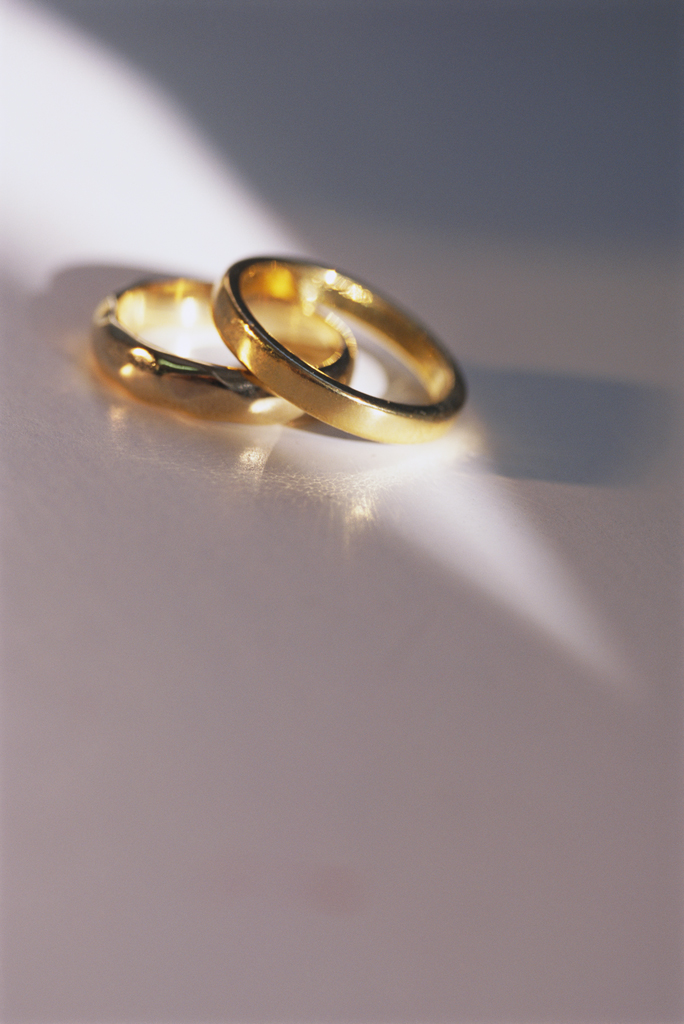 Two gold wedding bands resting on a wooden table, symbolizing commitment, love, and marriage.
