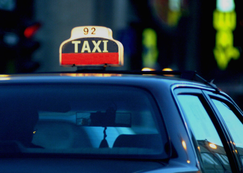 Illuminated taxi cab sign on the roof of a sedan