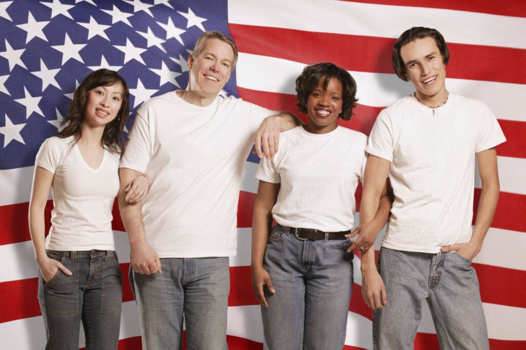 American flags, with a diversity of citizens standing in front. Men in jeans and t-shirts.