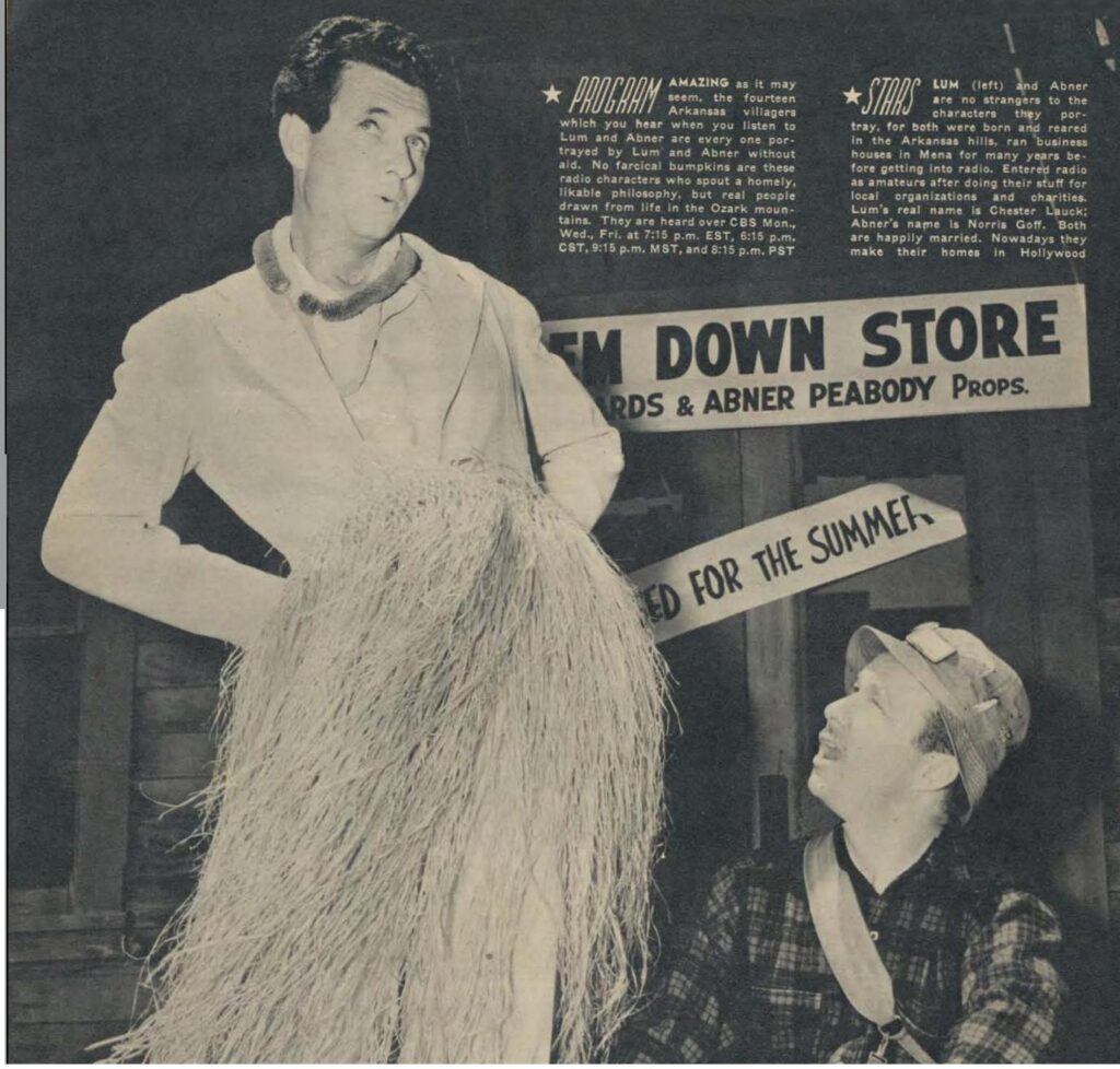 Two men dressed in traditional Hawaiian attire, Lum and Abner, are seen mid-dance in the center of a small store. Lum, on the left, is playing a ukulele while Abner on the right is swaying his hips and waving his arms. A small crowd is gathered around them, some clapping and others smiling. The store itself is cluttered with various items, including shelves of canned goods and hanging clothes, giving it a cozy and lived-in feel.