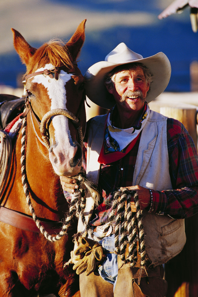 Cowboy standing next to his horse.