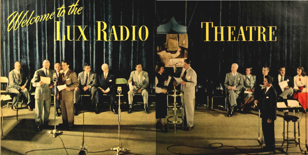 A black and white photograph of a group of people gathered around a microphone in a radio studio. The group includes several men and women in formal attire, some holding scripts, and others wearing headphones. In the center of the photo is a large microphone with the words "Lux Radio Theatre" written on it. The studio is dimly lit, with visible soundproofing panels and technical equipment in the background. The photo appears to be from the year 1948.